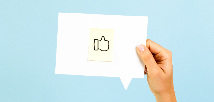 Hand holding speech bubble with "thumbs up" icon