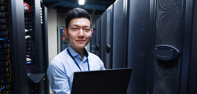 Young IT engineer standing near servers in data center