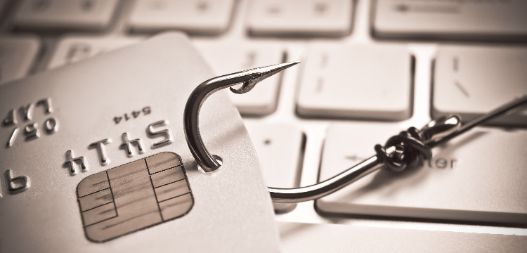 Closeup of credit card with fishing hook attached and laptop keyboard
