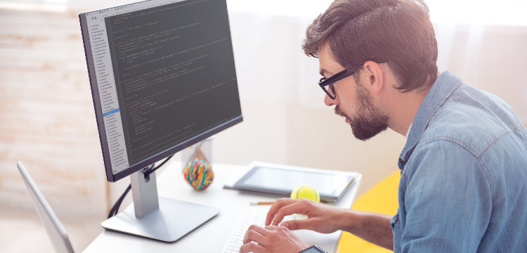 Young man typing code at computer in modern office setting